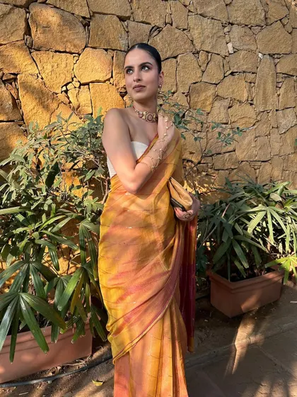The golden hour sunlight beautifully captures the radiant finish of this minimal makeup, complementing the warm tones of the Taneira saree.