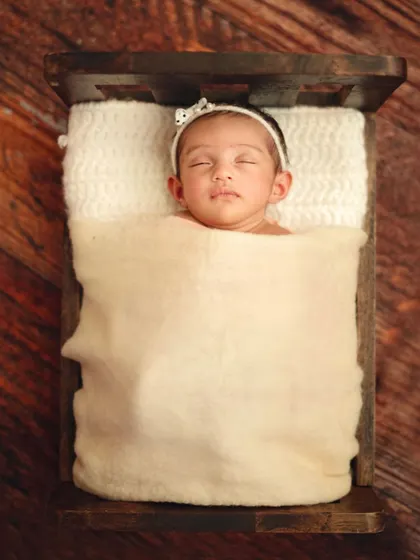 This portrait showcases the delicate features of a newborn girl, with a simple headband adding a touch of sweetness. The focus remains on her peaceful, sleeping face.