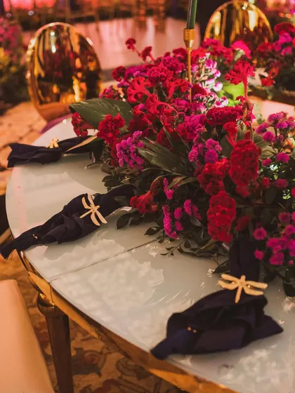 A beautiful table setting with a centerpiece of red and purple flowers, and custom dragonfly napkin holders adding a whimsical touch.
