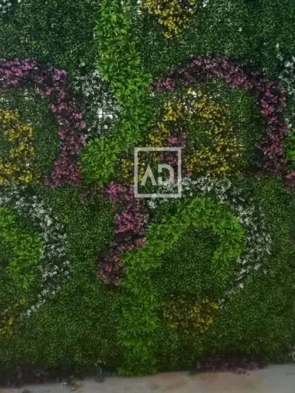 A full view of a custom-designed floral vertical garden. The swirling patterns of pink, yellow, and white flowers create a vibrant and artistic feature wall.
