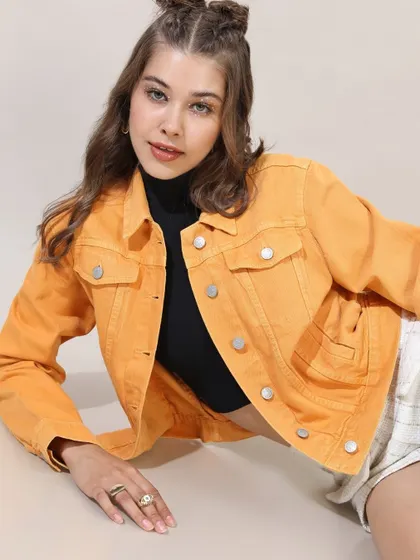 A vibrant look featuring a bright yellow denim jacket paired with a simple black top and shorts, showing how a pop of color can elevate an outfit.