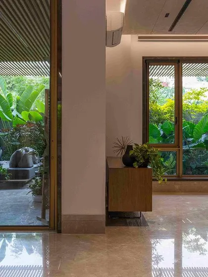 A seamless transition from a marble-floored interior to a verdant outdoor patio. The design uses large glass panels to dissolve the barrier between inside and out, making the garden a constant presence.