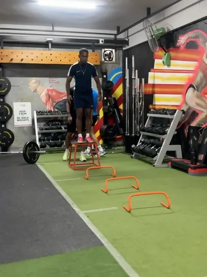 An athlete performs a depth jump over hurdles, a key plyometric exercise for improving reactive strength and acceleration. This is part of our progressive approach to developing power.
