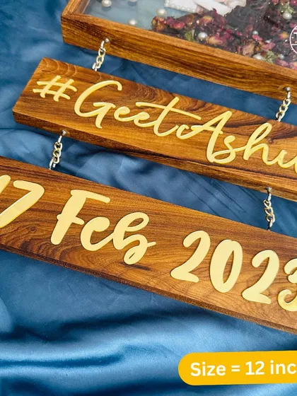 A close-up of the custom wooden plaques that hang below my 12-inch teakwood frames, featuring the couple's hashtag and wedding date.