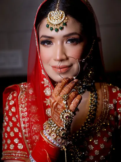 A beautiful portrait capturing the bride's gentle smile and the sparkle of her traditional jewelry, including her nath and maang tikka.
