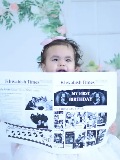 A close-up of the baby holding their personalized "First Birthday" newspaper, a creative and memorable prop.