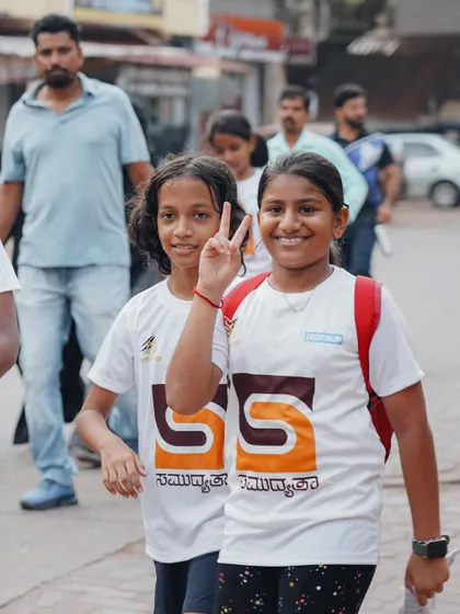 Two girls flashing a peace sign, enjoying the walk through their town.
