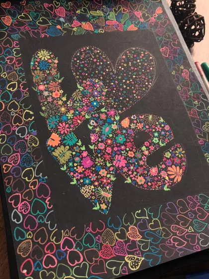 The completed "LOVE" floral artwork on a black sketchbook.