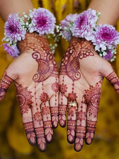 The bride's hands, adorned with intricate mehendi and delicate floral bracelets. These small, beautiful details are what make a pre-wedding look truly special.