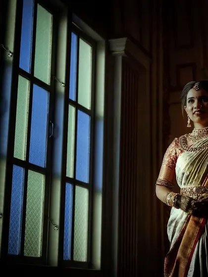 A bride standing by a stained-glass window, bathed in soft, dramatic light. This portrait has a timeless, painterly quality.