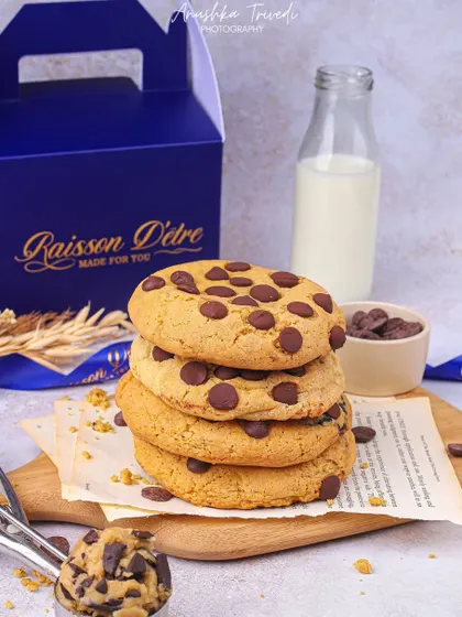 A classic stack of chocolate chip cookies styled with a bottle of milk and a cookie scoop for a nostalgic, homemade feel.