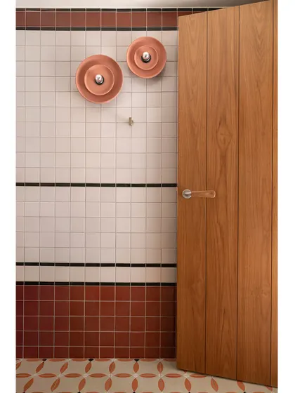 A detail shot of the bathroom wall, highlighting the playful, disc-shaped copper wall lights against the graphic tile pattern.