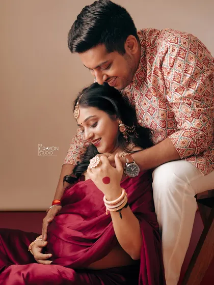 An intimate portrait showing the couple's deep connection. His gentle embrace from behind provides a sense of safety and love as they both look down with affection.