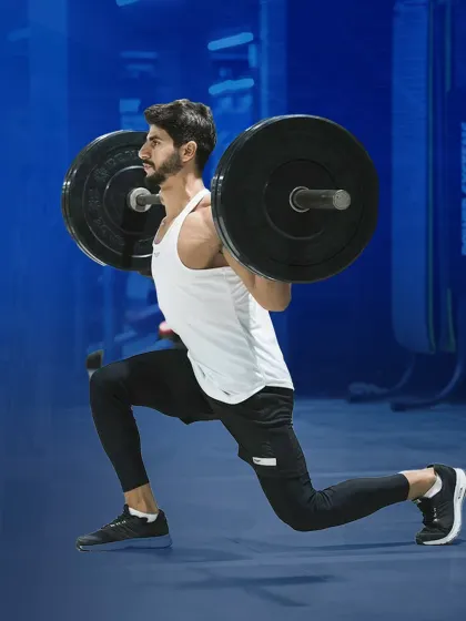 A man performs barbell lunges, a challenging exercise for building balanced leg strength and stability.