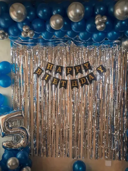 A close-up of the 25th birthday wall decoration, showing the details of the balloon arrangement and the 'Happy Birthday' banner.