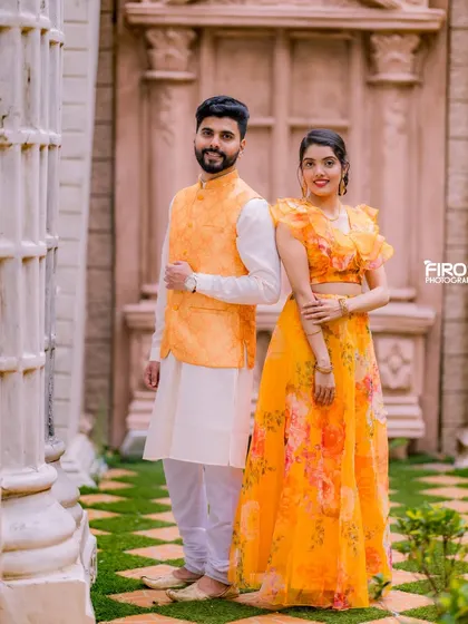 A lovely portrait of a couple in matching yellow and white traditional outfits. The soft, natural light and the garden setting create a fresh and romantic feel.