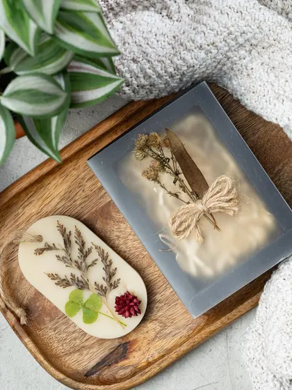 This oval wax tablet features a mix of dried leaves, clover, and a small flower, tied with a rustic twine. They are a great way to freshen up small spaces without a flame.