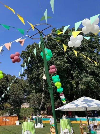 Thematic decorations for an outdoor jungle party, including colorful banners and balloon clusters hanging from a central pole.