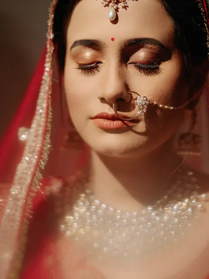 A sunlit close-up of the bride, her eyes closed in a moment of peace, highlighting her glowing makeup and jewelry.