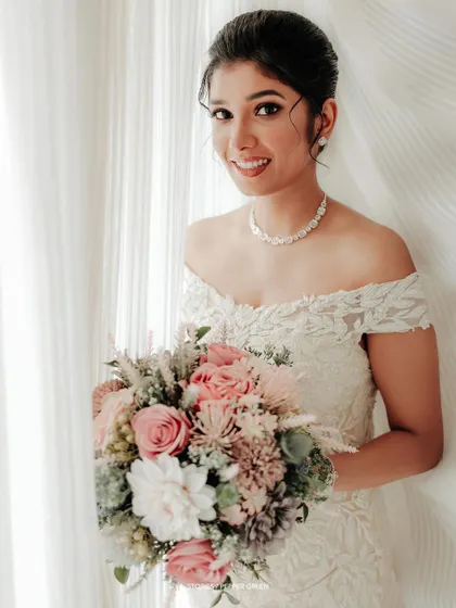 A classic bridal portrait, with the bride holding her bouquet and smiling warmly at the camera.