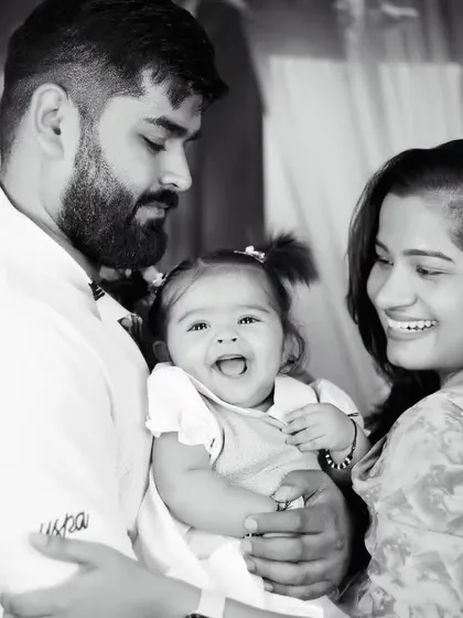 A happy black and white family portrait, capturing the love between parents and their laughing baby girl.