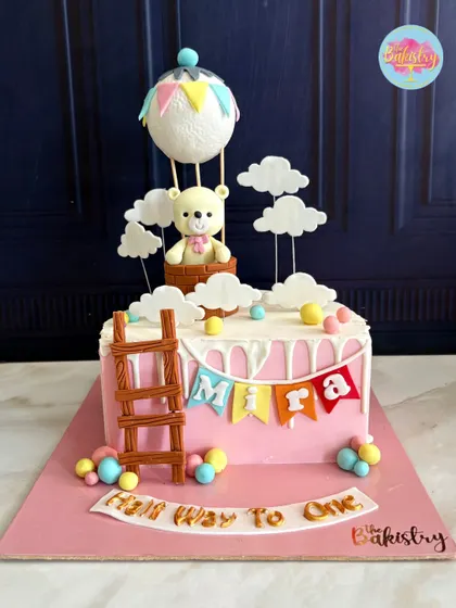 Celebrating Mira’s special milestone with this adorable "Half Way to One" cake. The design features a cuddly teddy bear in a hot air balloon, floating among the clouds.