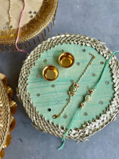 A serene mint green Rakhi thal with a silver gota border and a matching Bhaiya Bhabhi Rakhi set. A modern take on a traditional essential.