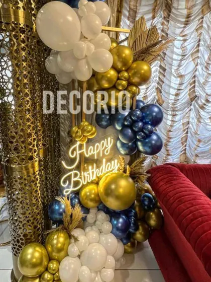 A compact yet luxurious balloon arrangement perfect for a smaller space. This decor features a mix of metallic blue, gold, and white balloons, dried palm leaves, and a neon sign.