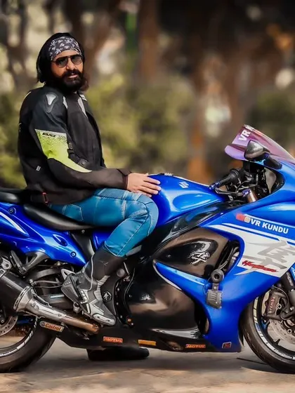 A profile shot of a rider on a vibrant blue Suzuki Hayabusa. This angle is perfect for showcasing the bike's iconic aerodynamic shape and the rider's cool, relaxed pose.