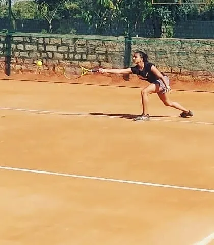 A female competitor lunges for a forehand shot during a UTR tournament, demonstrating focus and determination on the clay court.