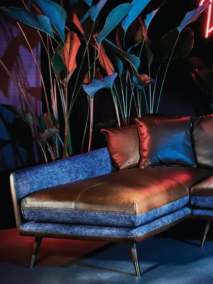 A close-up of the Volta Sofa's corner section, highlighting the beautiful contrast between the smooth leather and the textured blue fabric. This is craftsmanship designed to appeal to the senses.