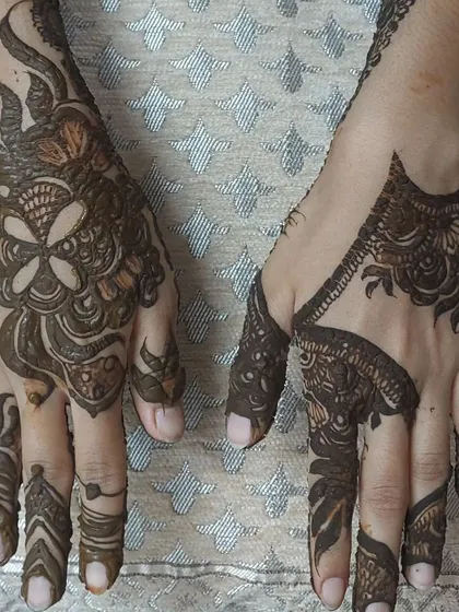 This image shows two different styles I can create. The hand on the left has a dense, bold floral pattern, while the hand on the right features a more geometric, spaced-out Arabian design.