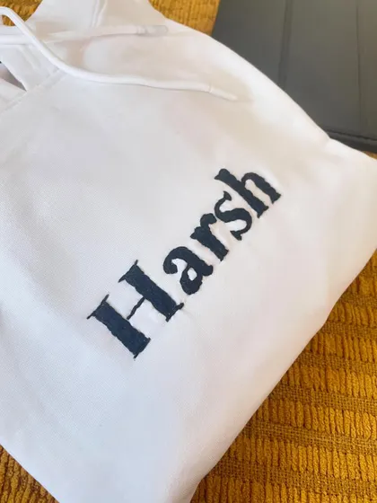 Sometimes simple is best. A clean, bold name 'Harsh' hand-embroidered on the chest of a crisp white hoodie.
