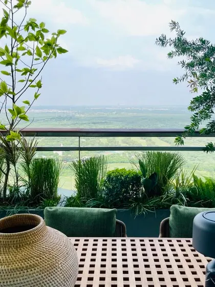 Another beautiful view of the horizon from the Camellias balcony garden. The dining table looks out over a golf course, framed by an olive tree and other lush grasses in planters.
