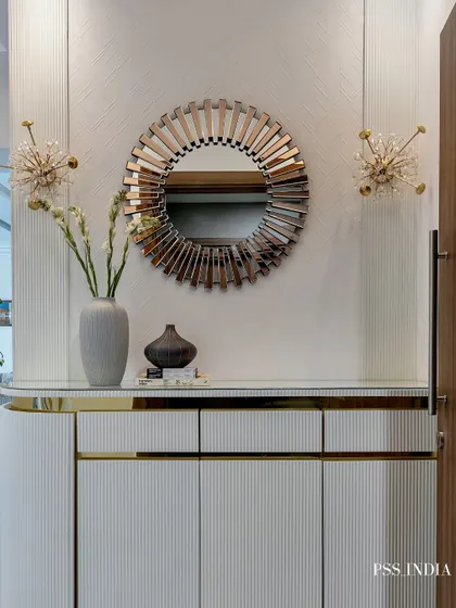 This entryway console makes a statement with its layers of texture and light. A sunburst mirror, star-like sconces, and a fluted white cabinet with gold accents come together for a look of modern glamour.