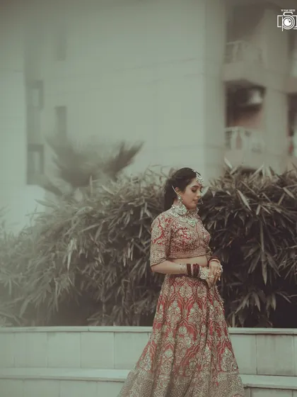 A full-length shot showing the bride in her magnificent lehenga. The soft, hazy filter gives this outdoor portrait a dreamy and romantic quality.