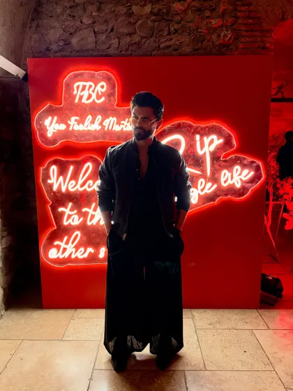 Standing against a neon sign, this all-black outfit really pops. It's a great look for a modern, urban event.
