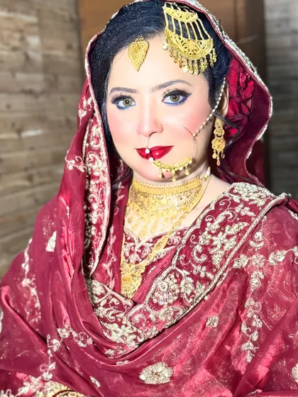 A stunning portrait of an HD Nikkah bride. Her bright blue eyes are beautifully contrasted with the warm tones of her makeup and the traditional red and gold of her attire.