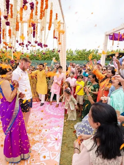 The joy of Haldi is in the celebration. Guests shower the happy couple with flower petals under a canopy of colorful drapes, a moment of pure, unscripted happiness that we love to witness.