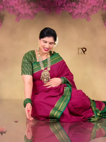A beautiful seated pose in a pink and green saree. The reflection on the floor and the floral elements create a dreamy, pond-like effect in our studio.