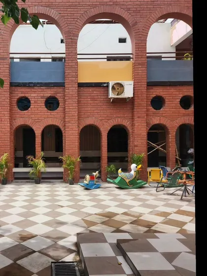 A straight-on view of the brick arcade in the school courtyard, showing the repetition of arches that provides shelter and defines the space. The design is both functional and aesthetically pleasing.
