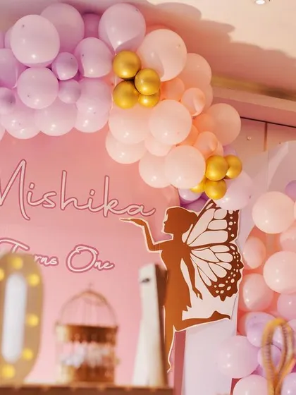 A duplicate image focusing on the elegant neon sign and the cascading pink, lavender, and gold balloon garland.