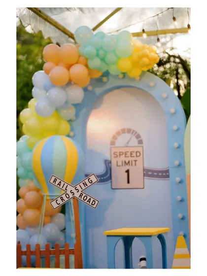 A close-up of a 'Railroad Crossing' sign and a hot air balloon prop, part of the detailed decor for our transportation-themed parties.
