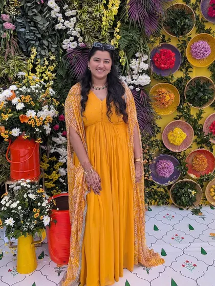 Wrapped in sunshine. This vibrant yellow georgette gown features a simple, flowing silhouette and is paired with a matching bandhani-print cape for a festive touch.