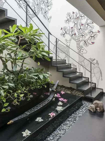 I love finding creative ways to bring nature indoors. This design integrates a tranquil water feature and a planter bed directly under the staircase, turning a forgotten space into a stunning and peaceful art piece with floating flowers.
