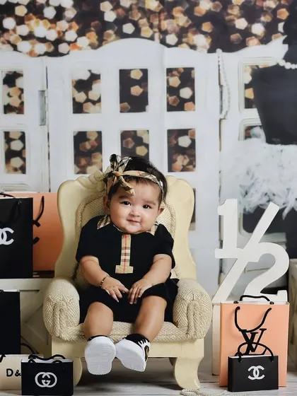 A full view of the fun and stylish shopaholic-themed set. This little one is surrounded by her favorite brands, showing off her big smile.