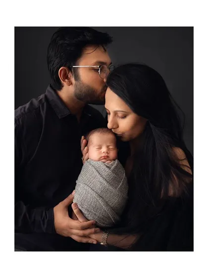 Parents sharing a kiss over their newborn baby's head, a beautiful symbol of their love.