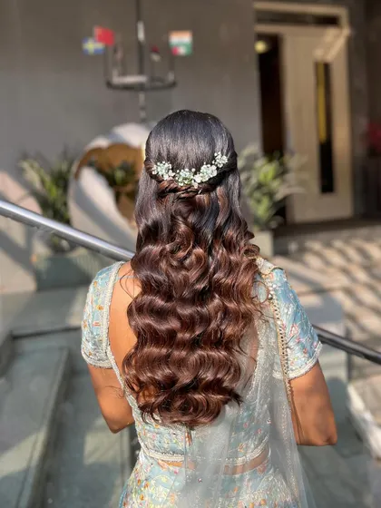 A shot of the beautiful half-up, half-down hairstyle with soft waves and a delicate hair accessory.