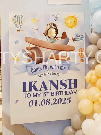 A personalized 'Come Fly With Me' welcome sign for a travel-themed first birthday, decorated with pastel balloons.