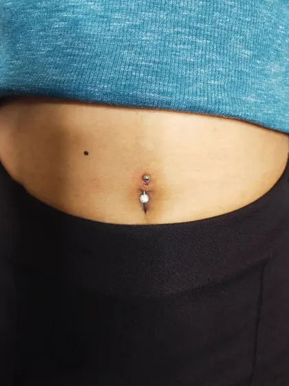 A navel piercing with a white pearl-style barbell. I can help you select from various jewelry materials and styles during your consultation.